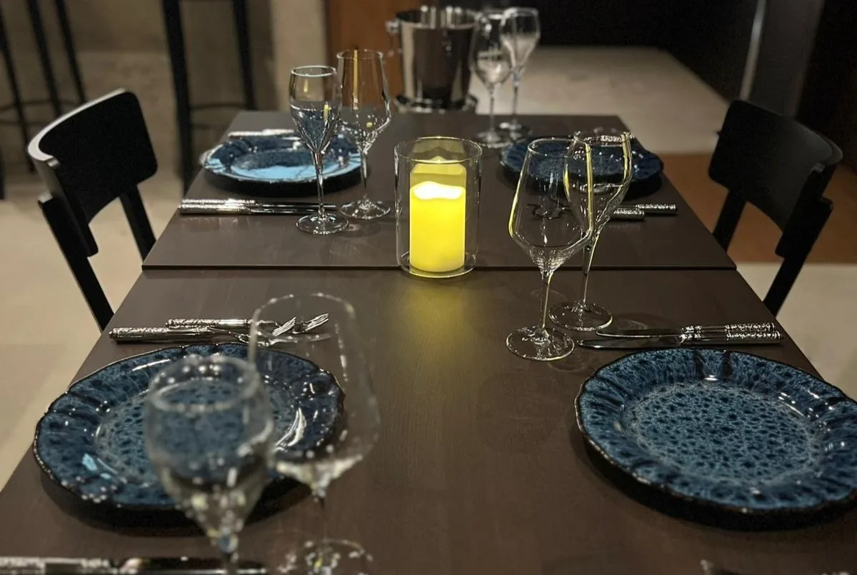 Auch ohne Stofftischtücher soll es im neuen Restaurant abends gediegen zugehen. Ein gedeckter Tisch im Seerestaurant «im Schilf»: Dunkelblaue, gemusterte Teller und Gläser stehen auf einem dunkelbraun gebeizten Holztisch.